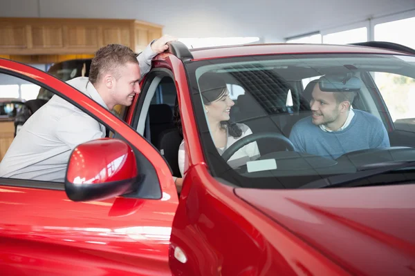 Paar luisteren naar een verkoper zittend op een auto — Stockfoto