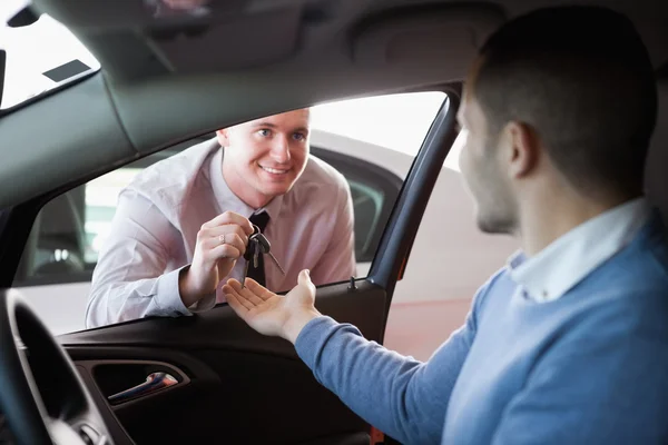 Smiling salesman giving keys to a customer — Stock Photo, Image