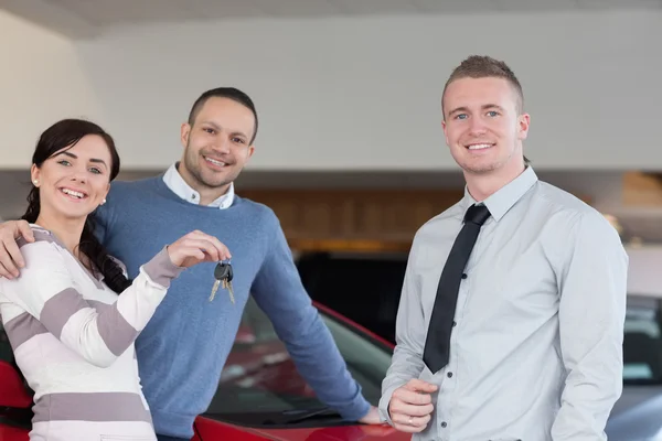 Salesman giving keys to an embracing couple — Stock Photo, Image