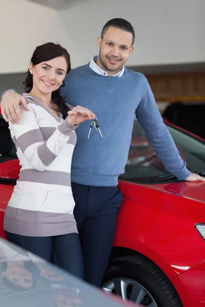 Glückliches Paar umarmt sich, während es Schlüssel hält — Stockfoto