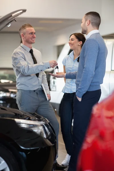 Salesman giving car key to a couple — Stock Photo, Image