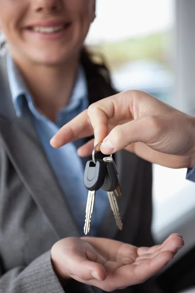 Hand holding keys over the hand of a woman — Stock Photo, Image