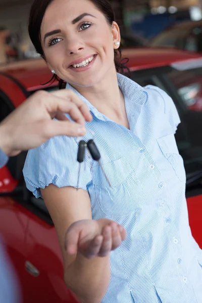 Mulher sorri ao receber uma chave de carro — Fotografia de Stock