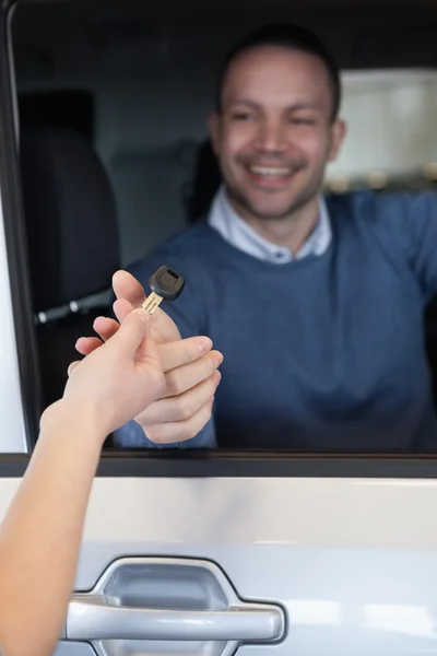 Homme dans une voiture recevant une clé — Photo