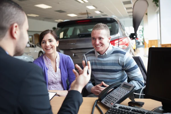 Couple smiling while talking with a salesman — Stock Photo, Image