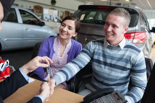 Happy couple shaking the hand of a salesman — Stock Photo, Image