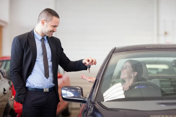 Salesman smiling while giving keys to a woman — Stock Photo, Image