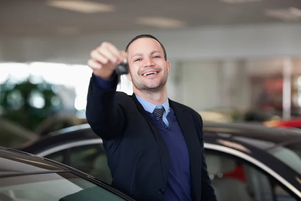 Sprzedawca stoi trzymając kluczyki do samochodu — Zdjęcie stockowe