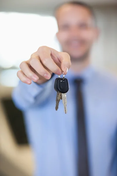 Säljare hålla bilnycklar genom hans fingertoppar — Stockfoto