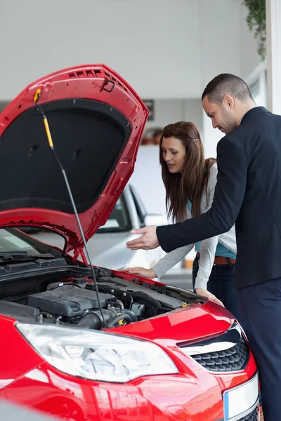 Prodavač ukazující auto motor — Stock fotografie