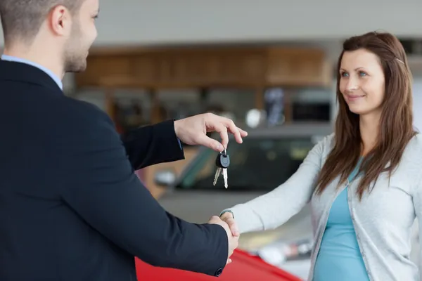 Salesman giving car keys while shaking hand of a woman — Stock Photo, Image