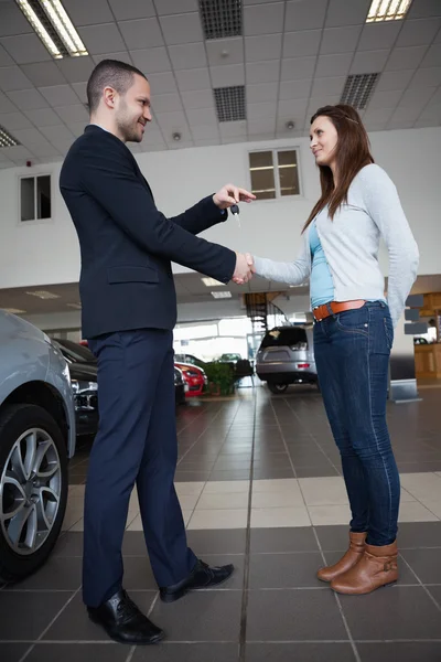 Salesman giving car keys while shaking hand of a client — Stock Photo, Image