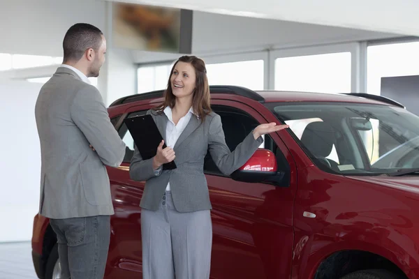 Donna d'affari che mostra un'auto a un cliente — Foto Stock