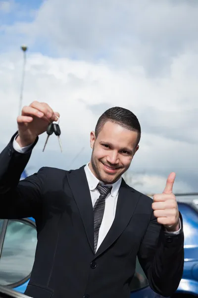 Man holding car keys while raising his thumb — Stock Photo, Image