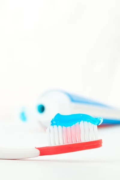 Escova de dentes vermelha ao lado de um tubo de pasta de dentes — Fotografia de Stock