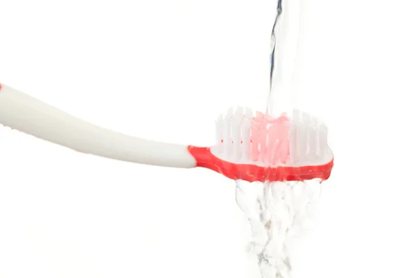 Agua cayendo sobre un cepillo de dientes rojo — Foto de Stock
