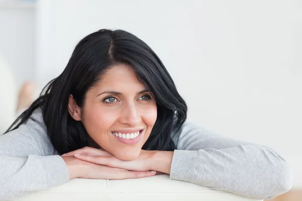 Smiling woman laying on a couch with her arms crossed under her Stock Image