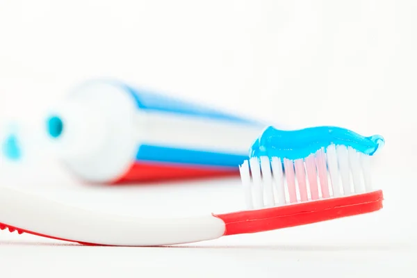 Tube of toothpaste next to a red toothbrush Royalty Free Stock Images