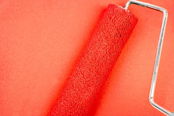 Red background with a paint roller — Stock Photo, Image