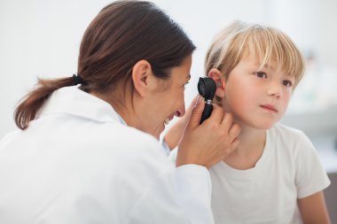 Doctor auscultating the ear of a child clipart