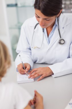 Doctor writing on a prescription note clipart