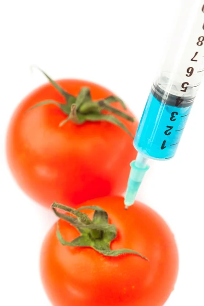 Syringe pricking a tomato — Stock Photo, Image