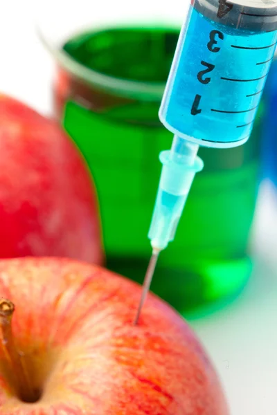 Close up of a syringe injecting liquid into an apple — Stock Photo, Image