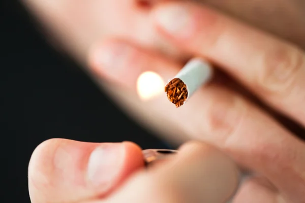 Zblízka si muž zapaluje cigaretu — Stock fotografie