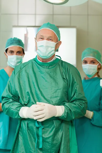 Cirujano uniendo su mano con pasantes detrás de él —  Fotos de Stock