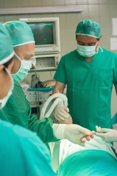 Equipe médica pegando um bisturi da mão de um colega — Fotografia de Stock