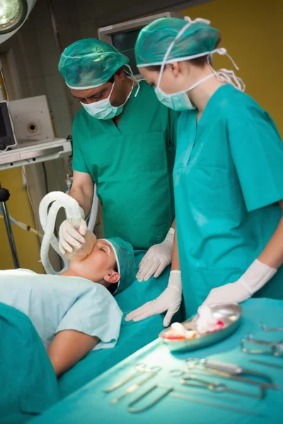 Surgeon working on a patient with a trolley with tools beside th — Stock Photo, Image