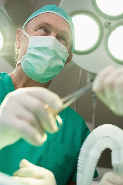 Chirurg lächelt, als er eine Chirurgenschere nimmt — Stockfoto