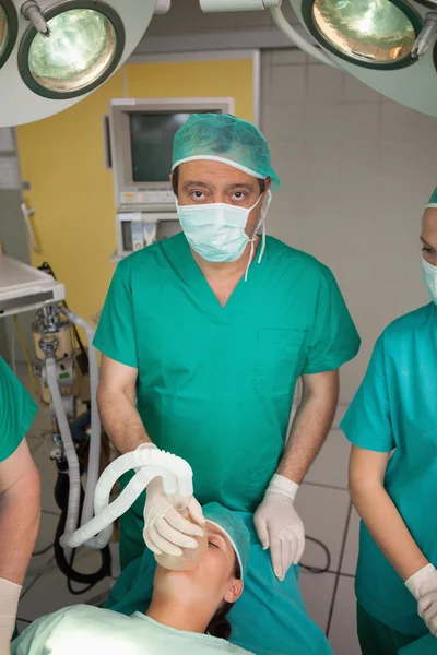 Хирург накладывает кислородную маску на лицо пациента — стоковое фото