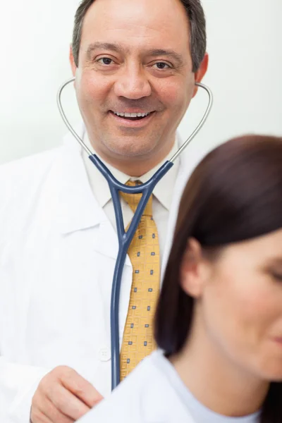 Usmívající se doktor auscultating pacienta — Stock fotografie