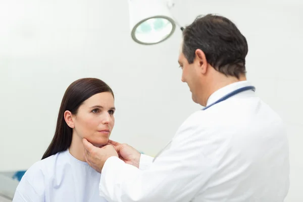 Läkare auscultating halsen på hans patient — Stockfoto