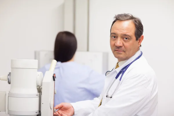 Doutor verificando uma máquina enquanto um paciente está tendo um mamógrafo — Fotografia de Stock