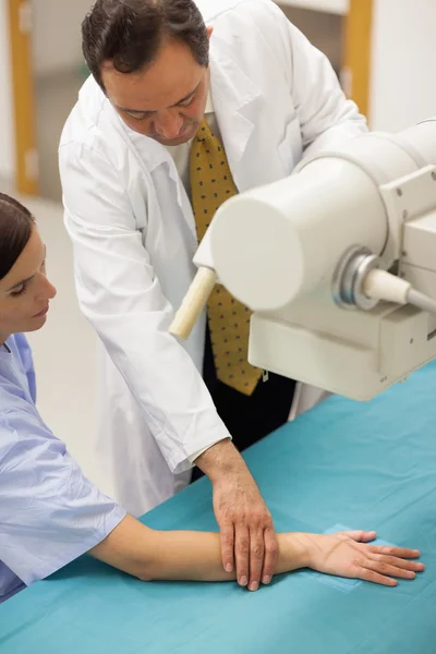 Médico colocando el brazo de un paciente sobre una mesa — Foto de Stock