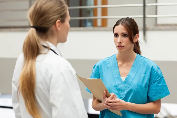 Infirmière tenant un dossier et parlant à un médecin — Photo