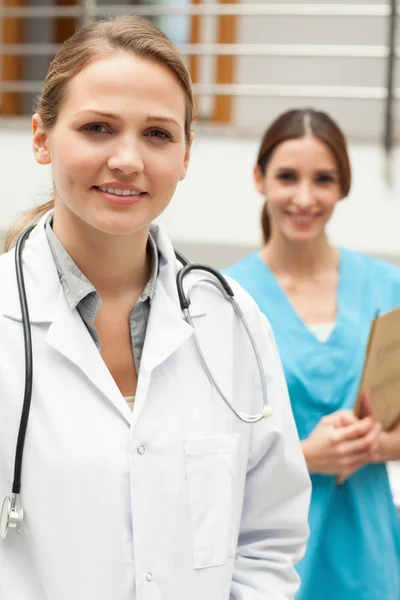 Doctor standing in a hospital reception with a nurse — Stock Photo, Image