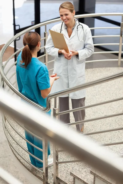 Médico segurando um arquivo enquanto fala com uma enfermeira — Fotografia de Stock