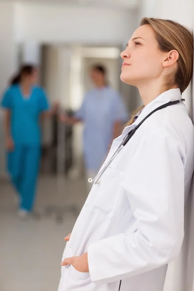 Doctor with her hands in her pockets against a wall — Stock Photo, Image