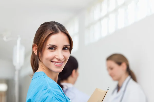 Donna sorridente mentre in piedi in un corridoio con un paziente e un — Foto Stock