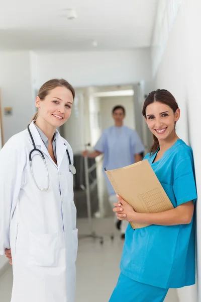 Médico y una enfermera contra una pared de pie lado a lado en un hal — Foto de Stock