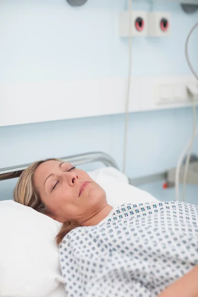 Female patient lying on a bed while closing her eyes — Stock Photo, Image