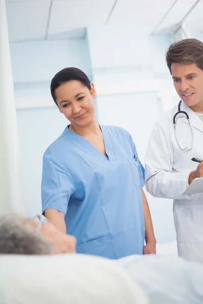 Médecin et infirmière regardant un patient — Photo