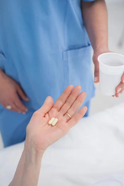 Krankenschwester schenkt einem Patienten Plastikglas — Stockfoto