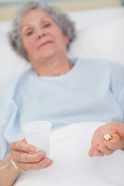 Paciente segurando drogas e vidro plástico em suas mãos — Fotografia de Stock