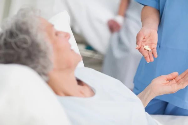 Nurse giving drugs to an elderly patient — Stock Photo, Image