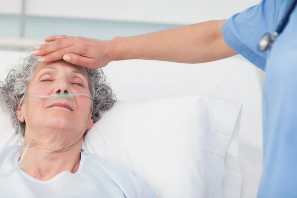 Nurse putting her hand on the forehead of a patient — Stock Photo, Image