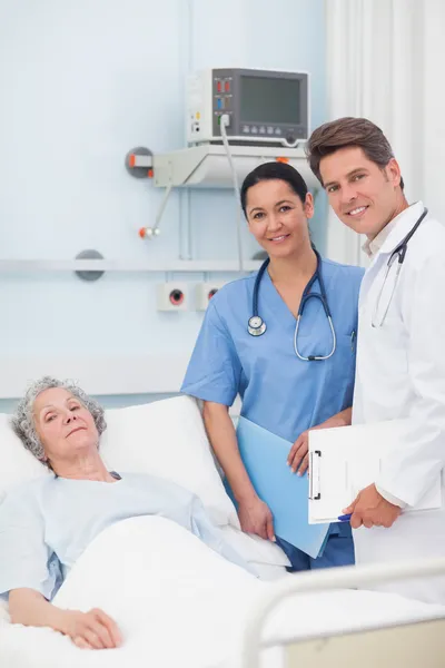 Paciente con su médico y enfermera mirando a la cámara — Foto de Stock